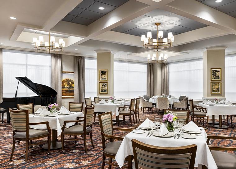 Amica Taunton dining room with set tables, chandeliers and a grand piano