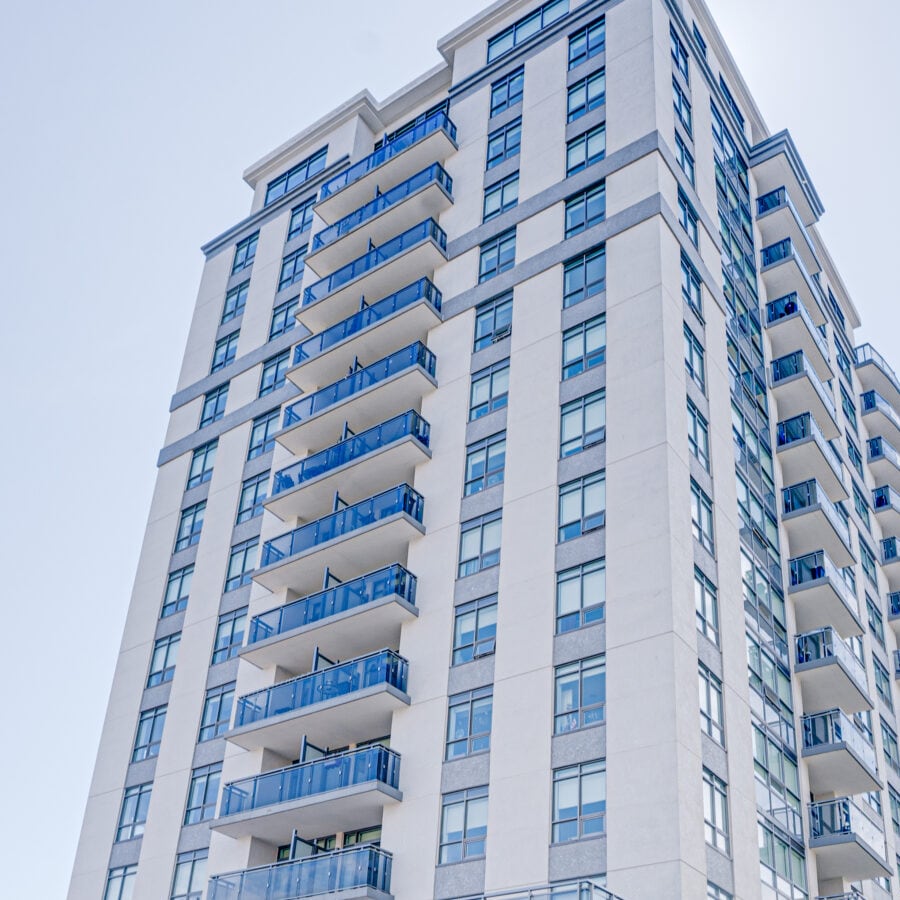 The upper floors of Royal Heights from the street, a column of blue glass balconies climbing a pale stone face